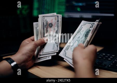 Hacker counting dollars at hideout Stock Photo
