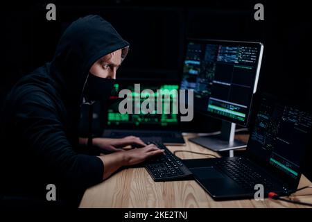 Hacker in mask coding on computer Stock Photo