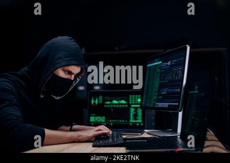 Hacker working in hoodie and mask Stock Photo