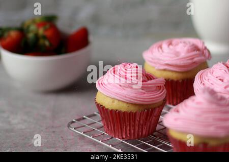 close up of vanilla muffins decorated with pink buttercream frosting on top Stock Photo