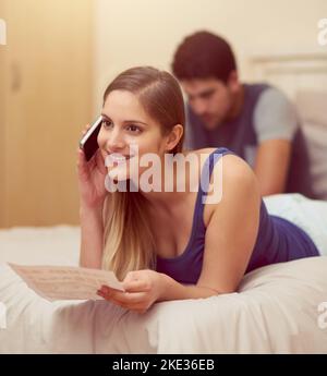 How nice to hear from you. a happy young woman talking on her cellphone while lying on her bed at home. Stock Photo