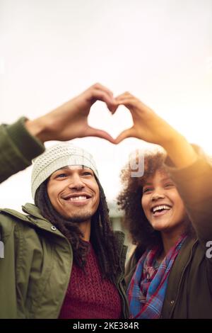 Making their love visible. two friends making a heart shape with their hands while standing outside. Stock Photo