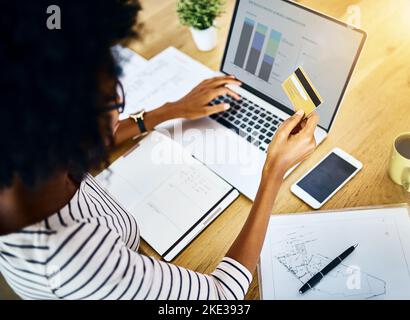 Time to pay the bills. Over the shoulder shot of a unrecognizable woman doing online banking on her laptop. Stock Photo