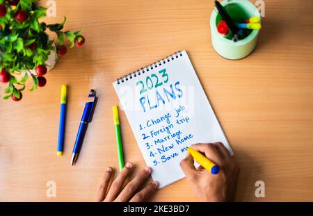 Top view of man writing new year 2023 plans on book - concept of strategy and goal setting and self help or development. Stock Photo