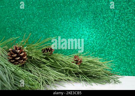 Natural pine tree Branches with cones on white table. Blurred green bokeh. Christmas, New Year. Copy space Stock Photo