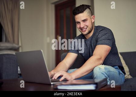 Work hard and make it happen. Portrait of a happy young man using his laptop to work from home. Stock Photo