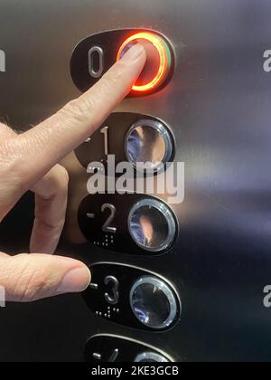 finger press elevator button with light. Going up to ground floor Stock Photo