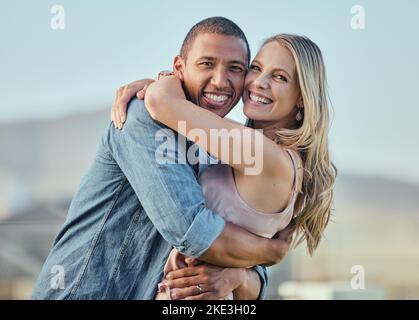 Happy interracial couple, hug and portrait smile for relationship happiness, travel or bonding in the outdoors. Man and woman hugging, smiling and Stock Photo