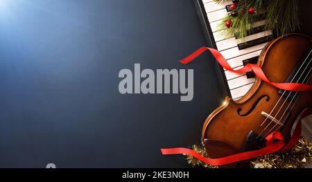 Christmas musical event concept background with piano and violin on black table and blue light. Top view. Stock Photo