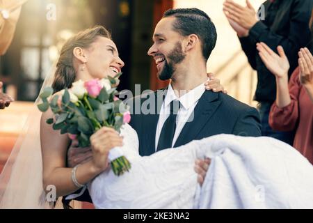 Love, wedding and man carrying woman at church after marriage ceremony with applause of friends and family. Happy, smile and celebration of married Stock Photo