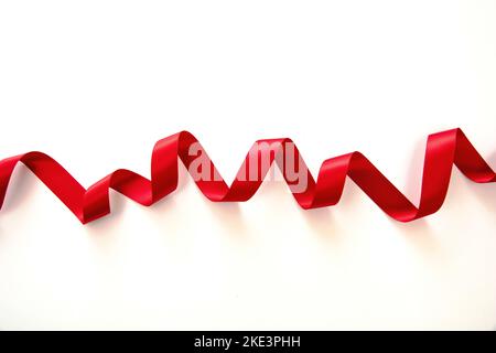 Red ribbon isolated on white background, close up view. Christmas decoration, Valentine day gift. Stock Photo
