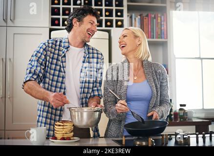 Theres always time for breakfast in this house. a happy couple making breakfast together at home. Stock Photo