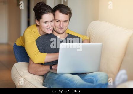 Working on their budget from the comfort of the couch. a loving couple using a laptop together at home. Stock Photo