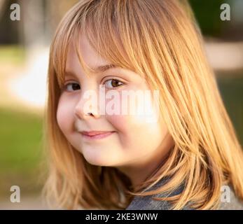 The sunshine days of childhood. Portrait of a little girl smiling in the garden. Stock Photo