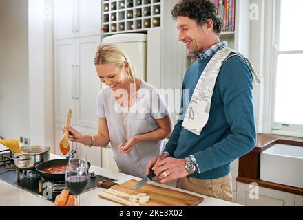 Happiness is homemade. a happy couple cooking dinner together in their kitchen. Stock Photo