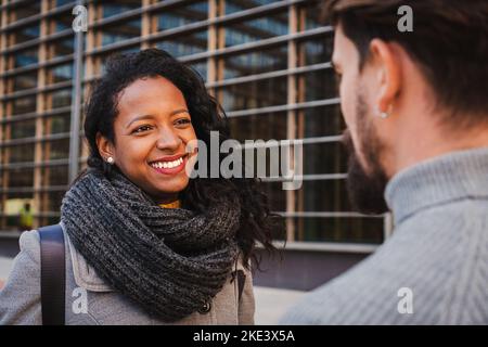 Close up portrait of two smart multiethnic business people conversing together outdoors, talking about job news in the office. One woman listening her Stock Photo
