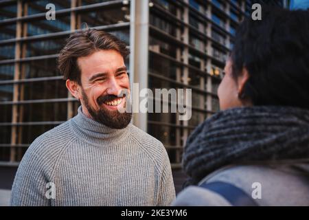 Close up portrait of two smart multiethnic business people conversing together outdoors, talking about job news in the office. One woman listening his Stock Photo