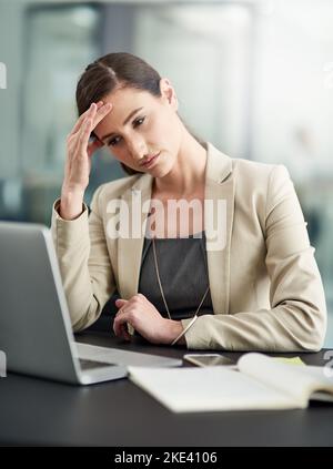 Work related stress - the struggle is real. a businesswoman looking stressed out at her office desk. Stock Photo
