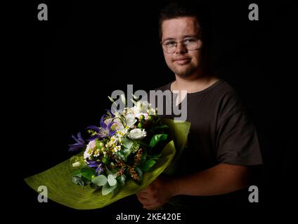 Young man with Down syndrome with a bouquet of flowers Stock Photo