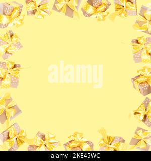 Frame of lot of wrapped gift boxes from craft papers with yellow polka dot ribbons and bows on yellow. Creative advertising background for any holiday Stock Photo