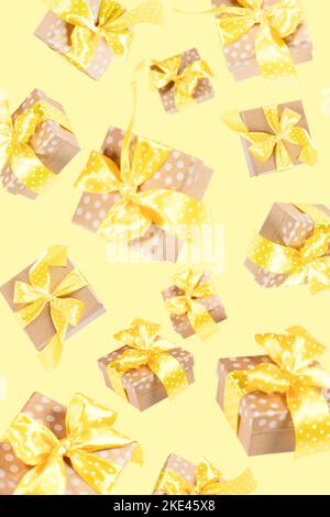 Wrapped gift boxes decorated with yellow ribbons and bows falling against yellow. Creative background of flying craft paper present boxes. Any holiday Stock Photo