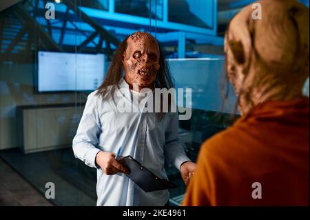 Zombie coworkers talking standing in boardroom at night Stock Photo