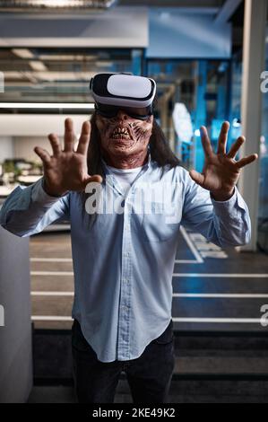 Zombie office worker using VR simulator headset Stock Photo