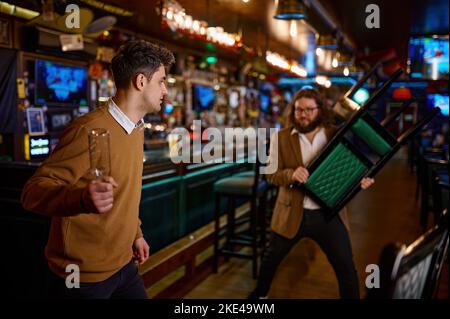 Two man hooligan football team fans get in bar fight Stock Photo