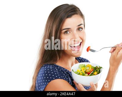 Eat clean, be happy. Studio portrait of an attractive young woman eating a healthy salad against a white background. Stock Photo