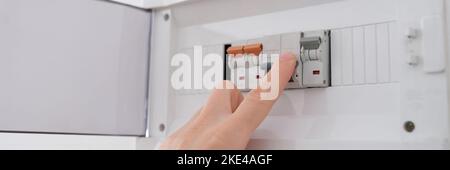 Man turns on toggle switch with hand closeup Stock Photo