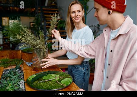 Two happy and smiling young florists working together at creative workshop Stock Photo
