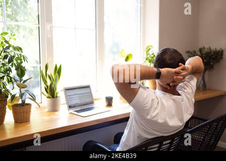 Young personal development coach answering the client by email by a laptop while having break in a coffee shop. Hipster guy searching the information Stock Photo