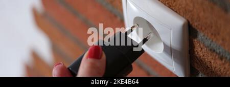 Woman holding hand and inserting plug into socket closeup Stock Photo