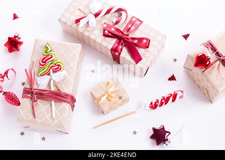 Three gifts with a red bow and candy cane on white background with sparkles. Flat lay style. Stock Photo