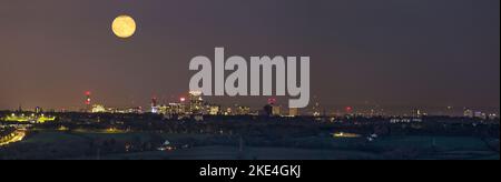Panoramic, night view from a distance of a full moon rising over Birmingham city centre, UK. Stock Photo