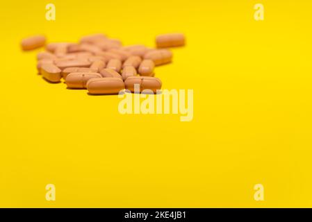 Several brown colored pills laid out on top of a blue surface. Medical supplies. Stock Photo