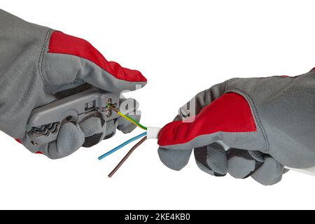 Electrician removes insulation from a three-core copper wire with a stripper. Hands in protective gloves with a stripper and an electric cable isolate Stock Photo