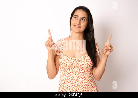 Young beautiful brunette hispanic woman wearing casual dress over isolated white background pointing fingers up with successful idea. Exited and happy Stock Photo