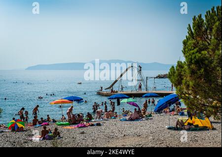 Beach on the Adriatic, Croatia, sunbathers on beach with slide shoot in the background calm day in summer Stock Photo