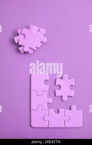 Purple jigsaw puzzle pieces on purple backgroun with pieces piled and ready to be fit. Stock Photo