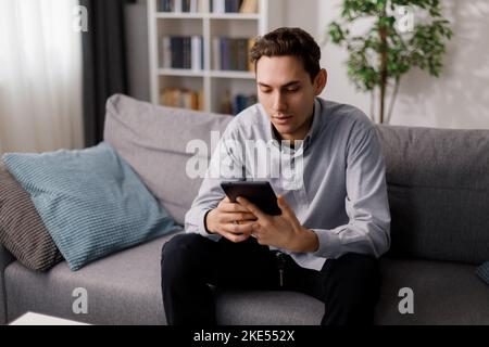 Man with tablet on couch Stock Photo