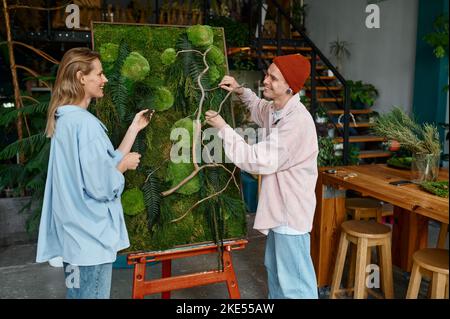 Two designers working on floral collage at florist shop Stock Photo