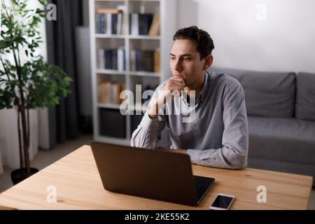 Thoughtful man with laptop Stock Photo
