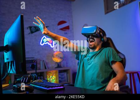 Playing VR googles headset exploring digital world, touching virtual reality subjects in neon lights Stock Photo