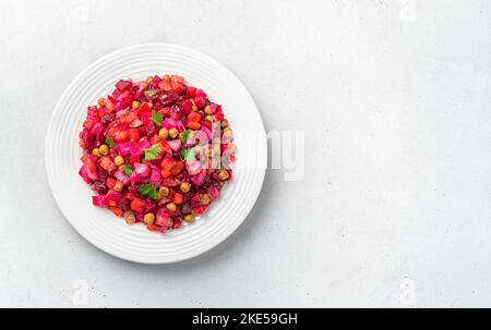 Vegetable salad vinaigrette in a white plate on a gray background. Stock Photo
