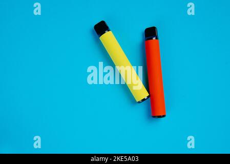 Two disposable e-cigarettes on a blue background. Electronic vape, an alternative to smoking cigarettes. Stock Photo