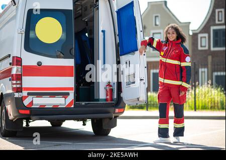 Happy paramedical professional standing near an ambulance Stock Photo