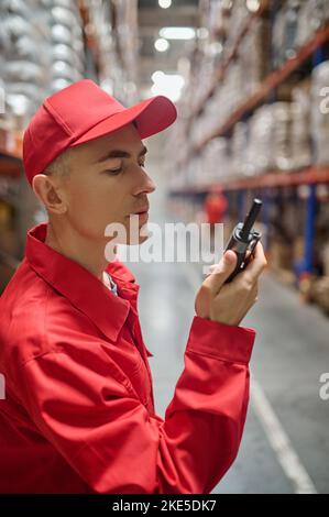 Worker using the two-way radio in the storage area Stock Photo