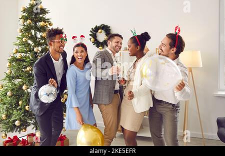 Funny happy young diverse friends drinking champagne and having fun at Christmas party Stock Photo