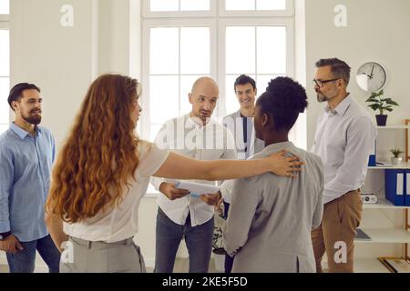 Corporative business training in office with people standing in round and listening man colleague. Stock Photo